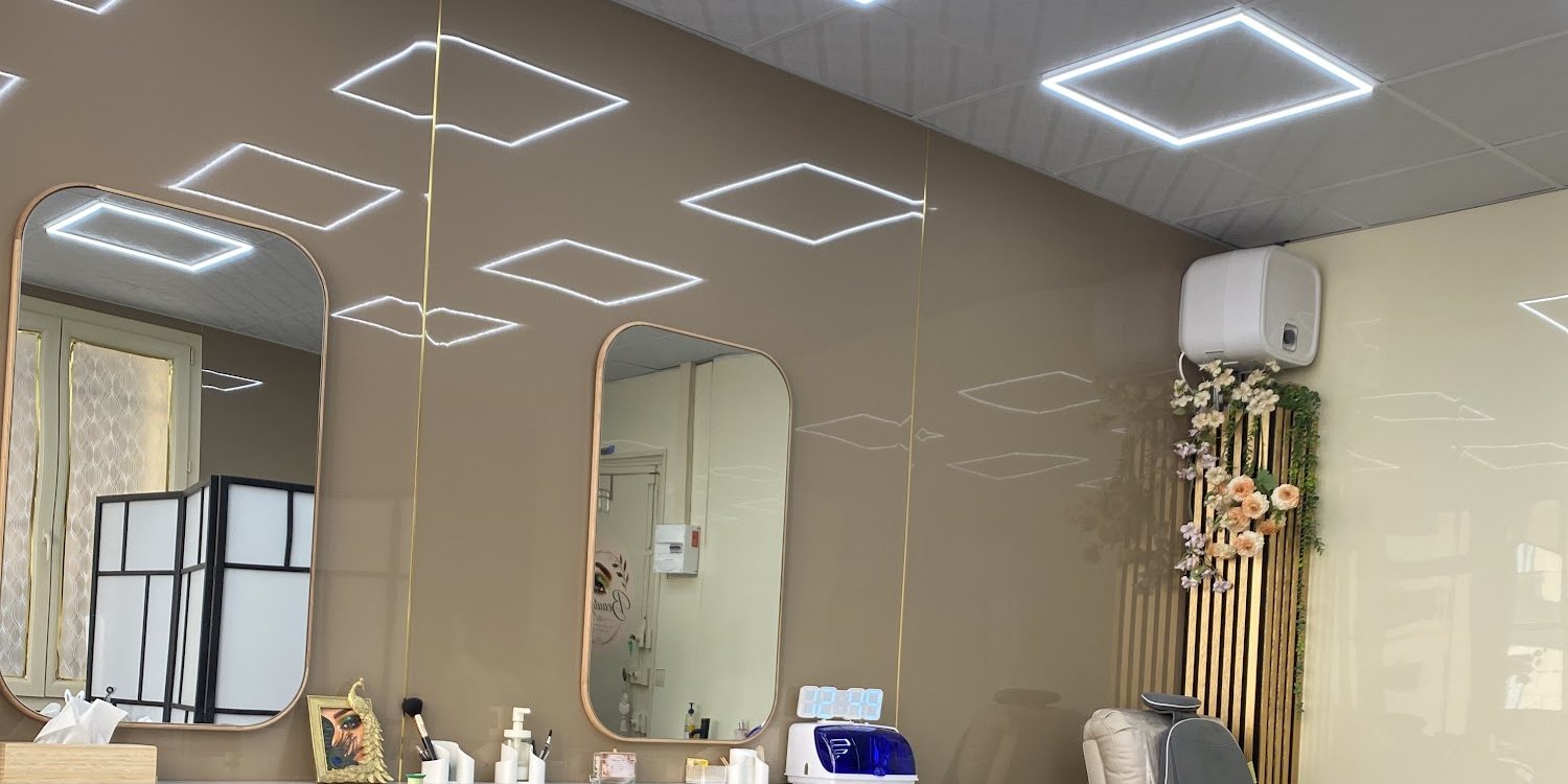 L'intérieur de l'institut : deux miroirs en arche, des néons en losange au plafond et un panneau de tasseaux dorés
